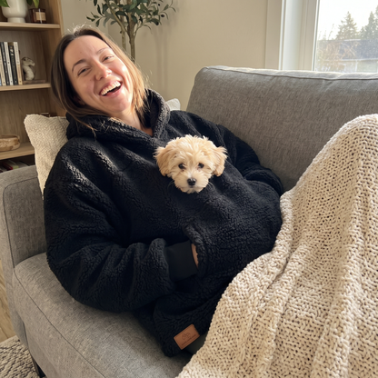 Black Pawket hoodie with a small puppy in the pocket on the couch